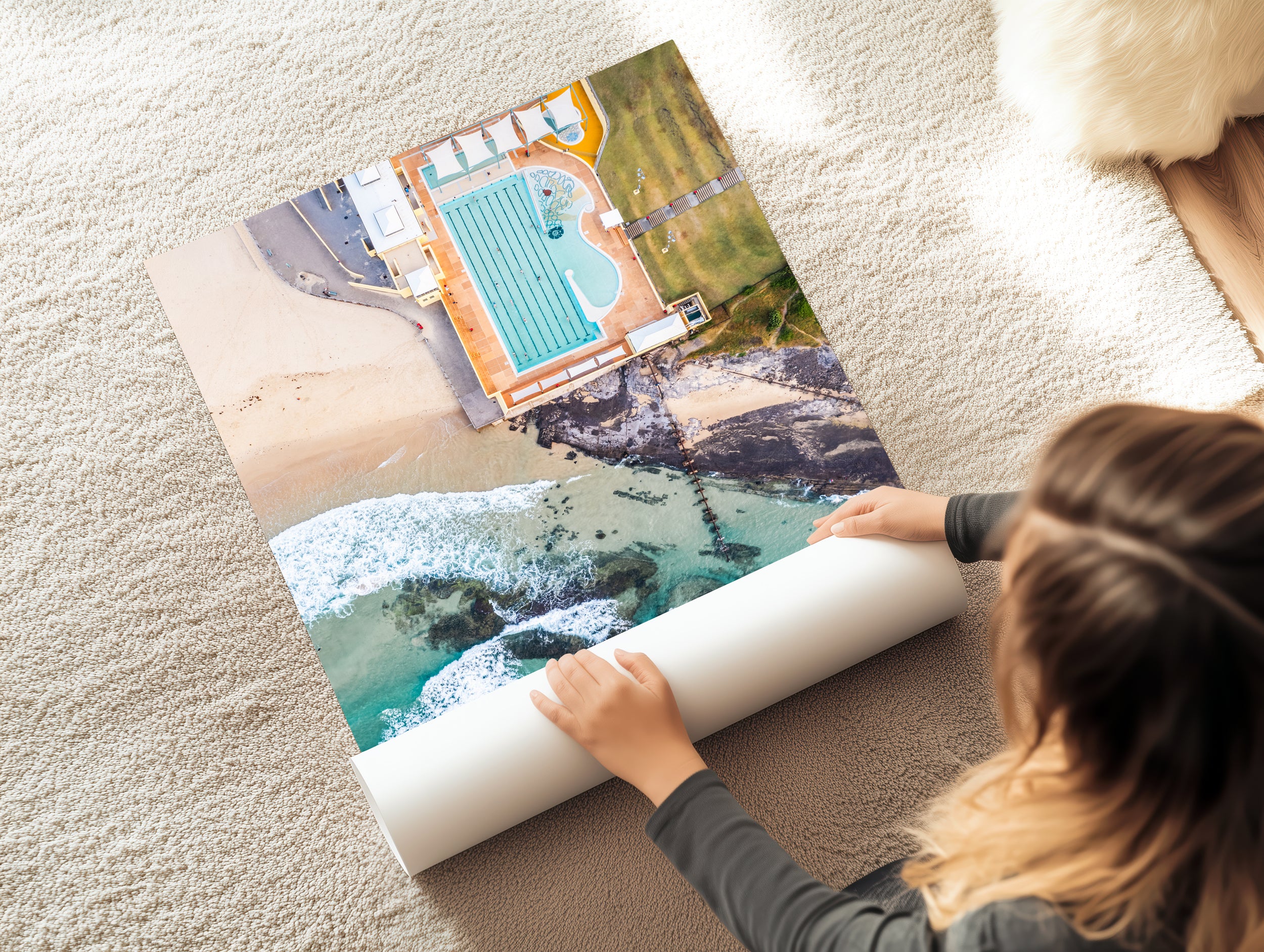Person unrolling a large scenic poster on a carpeted floor